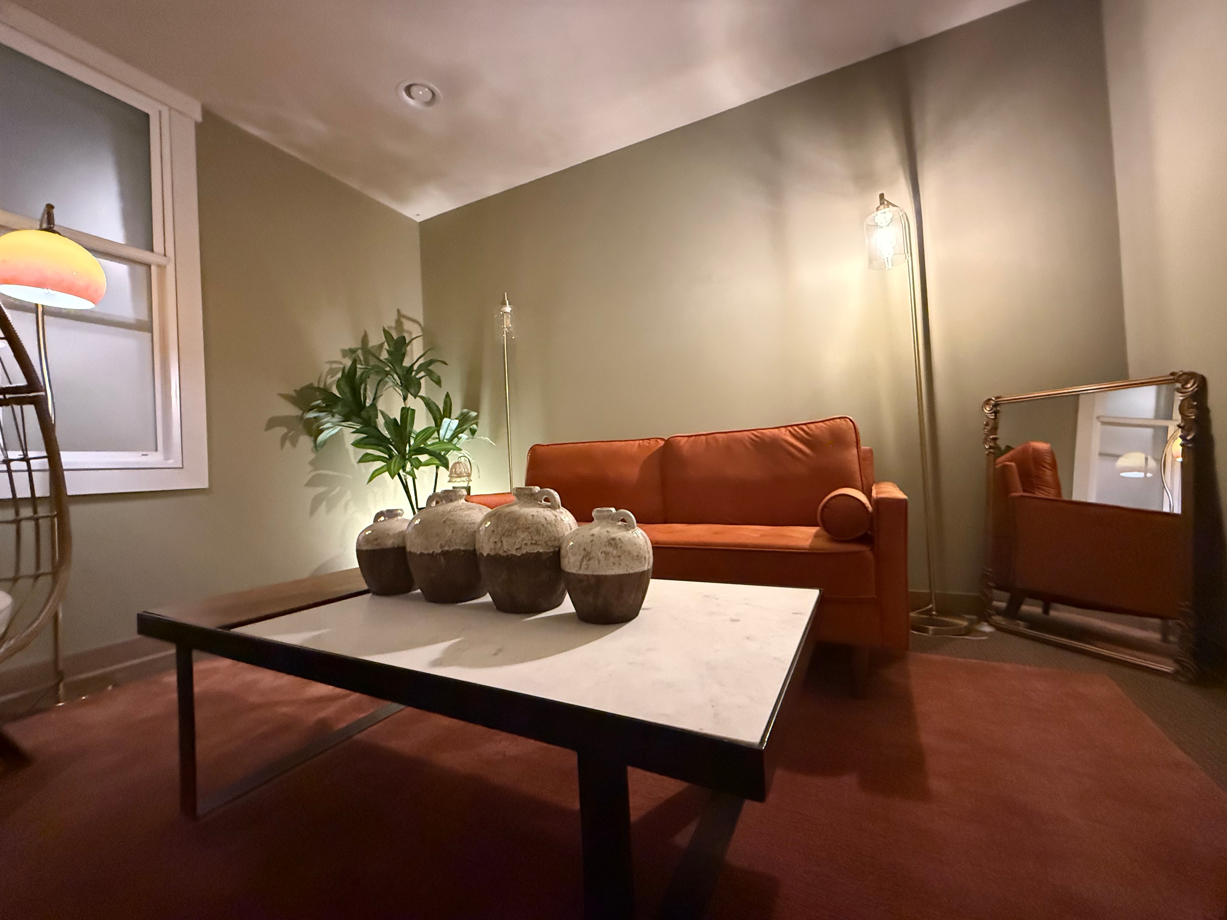 Lower front-facing view of the orange sofa and marble coffee table with warm lighting